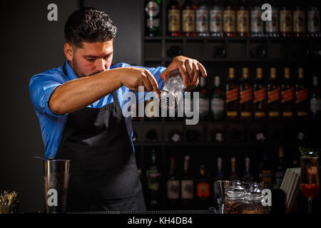 Expert barman is making cocktail at night club. Stock Photo