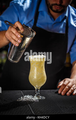 Bartender with shaker preparing pina colada cocktail at bar Stock Photo