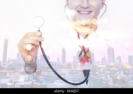 Smart healthcare hub disruption technology concept. Double exposure of professional doctor holding stethoscopes and metro city bokeh flare light in sm Stock Photo