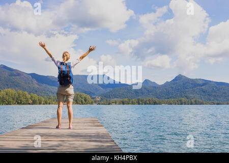 Happy female traveler with backpack raising arms after arriving to tropical paradise travel destination Stock Photo