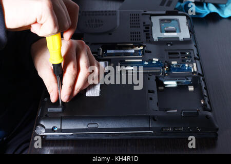 Closeup shot of male hands working on disassembling and cleaning circuit board in laptop using brush Stock Photo