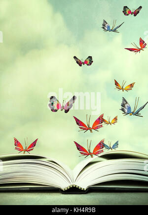 Artistic image of an open book and colorful butterflies that hover in the sky Stock Photo