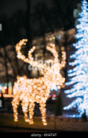 Natural Defocused Bokeh Background With Many Festive Lights Lamps In Shape Deer In Evening Night Illumination. Decorative Streets Elements In Christma Stock Photo