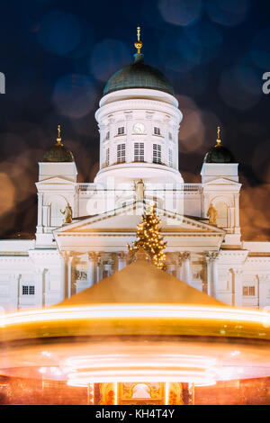 Helsinki, Finland. Xmas Market On Senate Square With Holiday Carousel And Famous Landmark Is Lutheran Cathedral In Winter Night. Stock Photo
