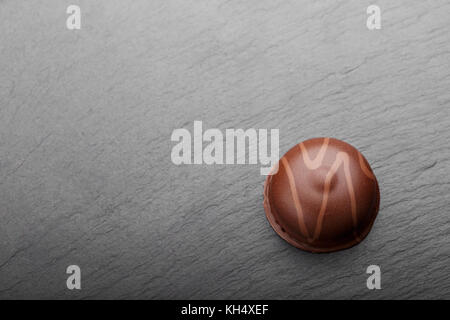 chocolate candy, top view, on a slate board, on a black background minimalism, space for text Stock Photo