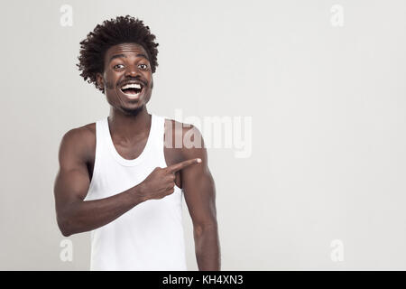 Man in white t-shirt showing finger at copy space. Studio shot. Gray background Stock Photo