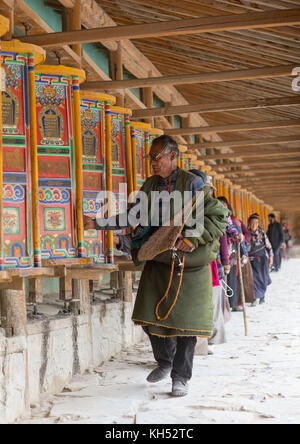 Tibetan pilgrims turning huge prayer wheels in Labrang monastery, Gansu province, Labrang, China Stock Photo