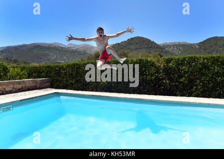 Teenage boy jumping into a private villa swimming pool Stock Photo