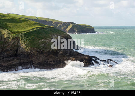 A choppy sea sends waves crashing against the rocks near Port Isaac on the north Cornwall coast, UK, on a sunny autumn day. Stock Photo