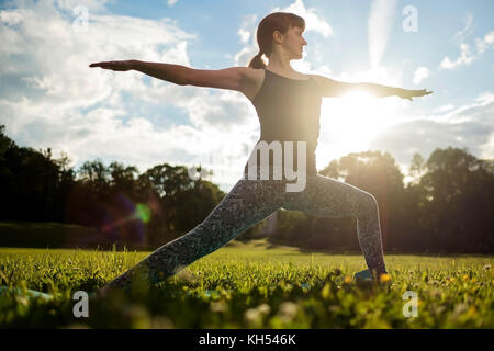 Beautiful young caucasian woman practices yoga asana Virabhadrasana 1 Stock Photo