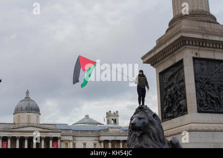 A protestor waves the Palestinian flag under Nelson's Column on the centenary of the Balfour Declaration,  Trafalgar Square, London Stock Photo