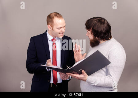 The professor and student standing opposite each other, discuss the report in a gray folder, on a gray dark background Stock Photo