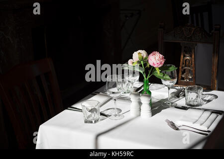 Proud Stanmer House, Brighton. Formal dining place setting with white linen and flowers, bathed in sunlight. Stock Photo