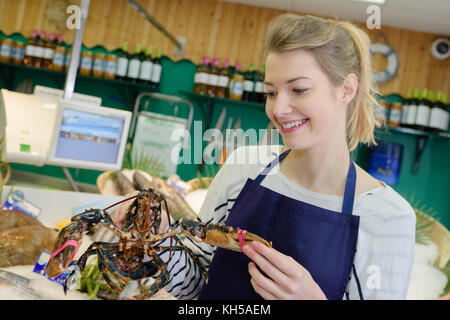 female working holding a lobster in a fish supermarket Stock Photo