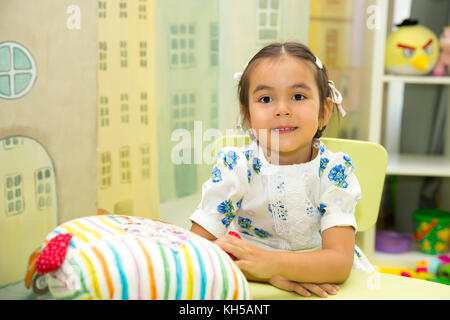 Adorable asian, Kazakh child girl in nursery room. Kid in kindergarten in Montessori preschool class. Stock Photo