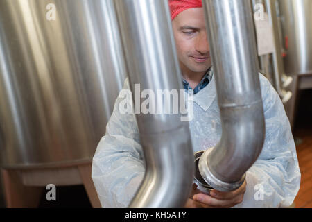 factory worker in white suit is checking pipes Stock Photo