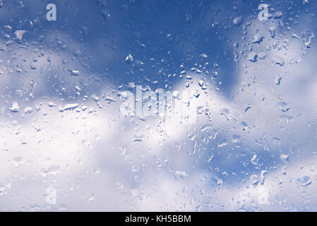 Blue sky and clouds viewed from a window with rain drops Stock Photo