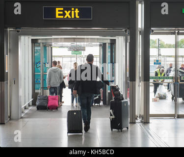 People leaving Stansted Airport via EXIT sign from International Arrivals Stock Photo