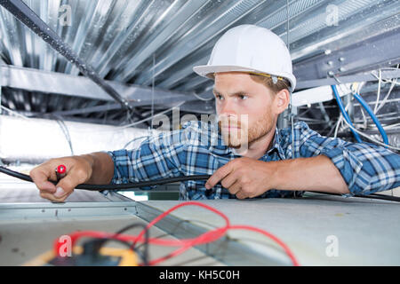 electrician sets the lamp on the ceiling Stock Photo