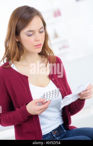 Woman holding medication and reading information leaflet Stock Photo
