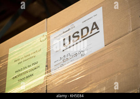 Pallets of USDA Emergency Food Assistance Program (TEFAP) commodities wait on the Houston Food Bank commodity warehouse shelves for movement to packing lines or delivery to food pantries; pallets in the aisles are loaded with disaster assistance packages (those with orange wrapping have USDA Foods in them), and are ready for delivery or distribution to those in need, in Houston, TX, on September 22, 2017. Houston Food Bank Operations Associate Director Marly Maskill provided the following information; in general, the food bank usually receives approximately 10 trucks per day and distributes ap Stock Photo