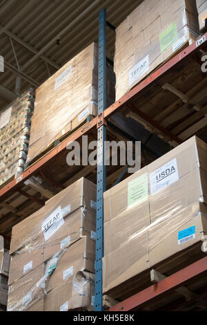 Pallets of USDA Emergency Food Assistance Program (TEFAP) commodities wait on the Houston Food Bank commodity warehouse shelves for movement to packing lines or delivery to food pantries; pallets in the aisles are loaded with disaster assistance packages (those with orange wrapping have USDA Foods in them), and are ready for delivery or distribution to those in need, in Houston, TX, on September 22, 2017. Houston Food Bank Operations Associate Director Marly Maskill provided the following information; in general, the food bank usually receives approximately 10 trucks per day and distributes ap Stock Photo