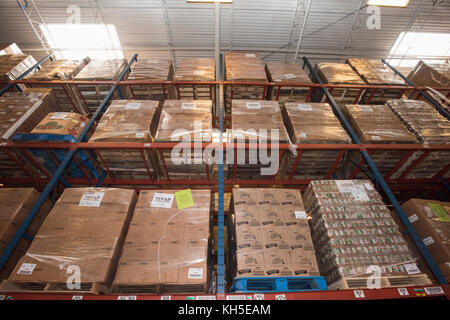 Pallets of USDA Emergency Food Assistance Program (TEFAP) commodities wait on the Houston Food Bank commodity warehouse shelves for movement to packing lines or delivery to food pantries; pallets in the aisles are loaded with disaster assistance packages (those with orange wrapping have USDA Foods in them), and are ready for delivery or distribution to those in need, in Houston, TX, on September 22, 2017. Houston Food Bank Operations Associate Director Marly Maskill provided the following information; in general, the food bank usually receives approximately 10 trucks per day and distributes ap Stock Photo