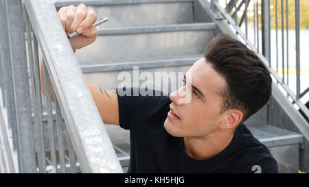 Man writing on banister or handrail Stock Photo