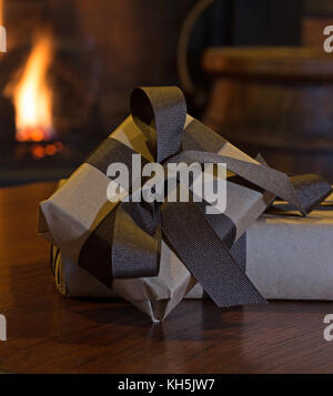 Two brown presents on a table with a fireplace in background Stock Photo