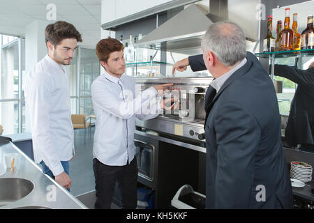 young workers learning how to clean a coffee machine Stock Photo