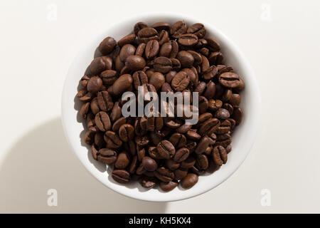 Selection of roasted coffee beans seed. Top view of grains in a bowl. White background. Stock Photo