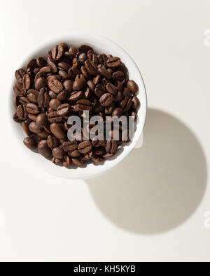 Selection of roasted coffee beans seed. Grains in a bowl. Shadow over white table. Stock Photo