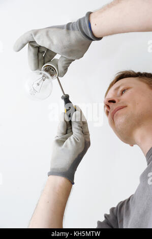 Man in gray gloves connects the light bulb. Stock Photo