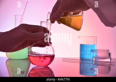 Chemical professional investigating with different substances in flasks. Horizontal composition. Front view