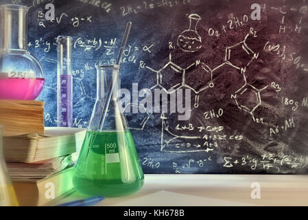 Classroom desk and drawn blackboard of chemistry teaching with books and instruments. Chemical sciences education concept. Horizontal composition. Fro Stock Photo