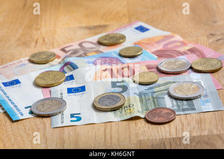 Several Euro bank notes and coins close up on wooden table Stock Photo