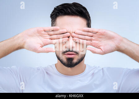 Tired young programmer closing his eyes after long hours of work Stock Photo
