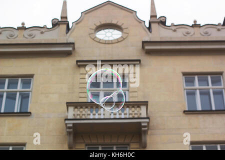 Big soap bubble flies through air in city against old-fashioned house Stock Photo