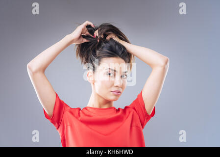 Cheerful young woman looking glad while changing her hairstyle Stock Photo