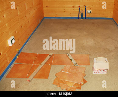 A concrete floor in a newly built wooden (fir) house which is about to be tiled. The blue foam material is protecting the wood from the concrete and a Stock Photo
