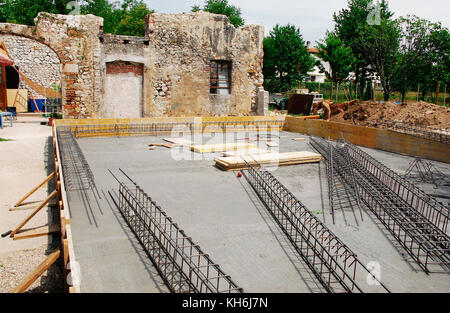 Steel reinforcement cage used in the construction of building foundations. The foundation site is surrounded by wooden shuttering and the steel cages  Stock Photo