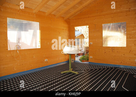 A hydronic closed loop underfloor heating system laid out on molded insulated panel in EPS with a spooling table inside a partially constructed wooden Stock Photo