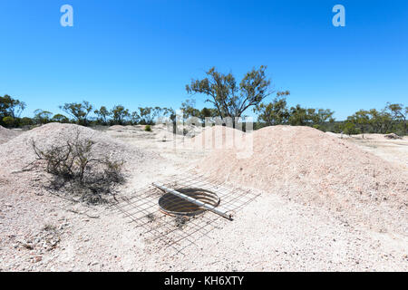 Opal mining shaft with mullock heaps and mining equipment in the ...