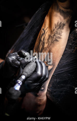 Tattoo artist doing tattoos in tattoo salon Stock Photo