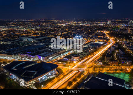 MUNICH, GERMANY - November 3, 2017: The lit BMW headquarters and BMW Welt with light trails from traffic during blue hour from above Stock Photo