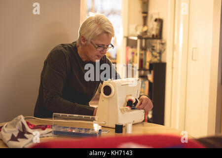 Senior woman using a sewing machine at home Stock Photo