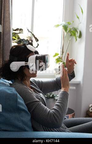 Woman using virtual reality headset at home Stock Photo