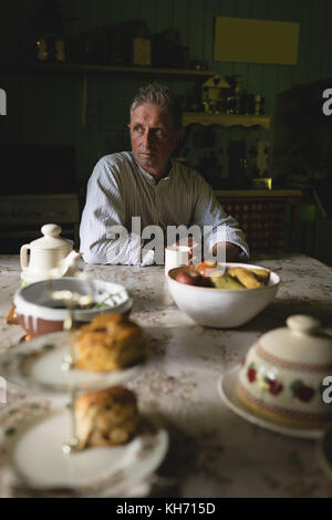 Thoughtful senior man having coffee in kitchen at home Stock Photo