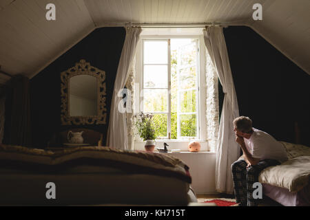 Thoughtful senior man relaxing in bedroom at home Stock Photo