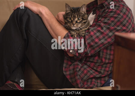 Man sitting with his cat on sofa at home Stock Photo